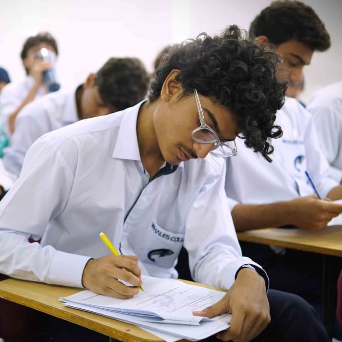 A Whales College student writing during the first term examinations